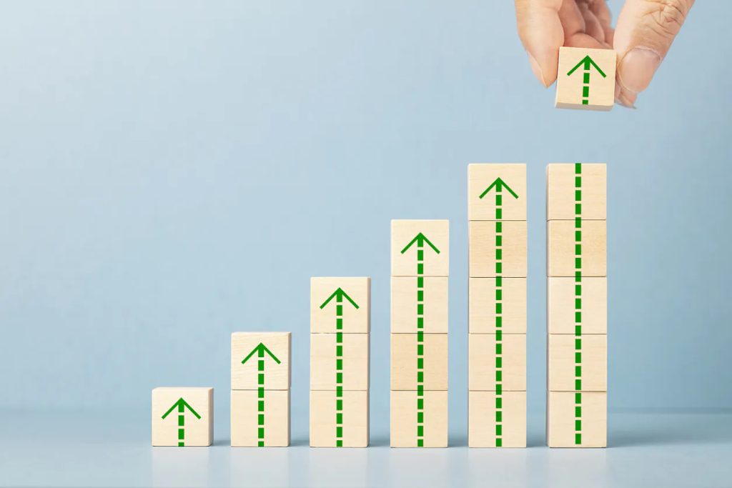 Wooden blocks arranged in ascending order, each with green arrows, symbolizing growth.