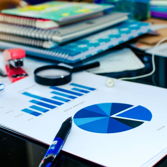 cluttered desk with a focus on a paper showing blue bar and pie charts